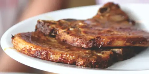 Dos jugosas chuletas de cerdo a la parrilla, doradas y listas para disfrutar.
