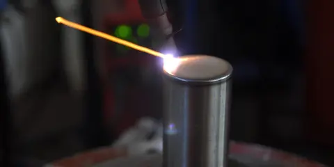 Un arco di saldatura GTAW illumina un cilindro metallico. La precisione del processo crea un cordone perfetto.