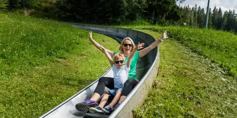 Radość na Gubałówce! Mama z synem zjeżdżają na torze saneczkowym, sprawdzając cennik.