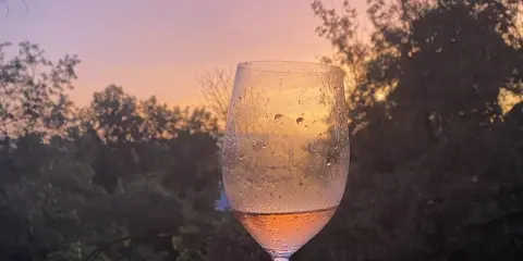 Un calice di vino rosato riflette il tramonto sulle dolci colline del Chianti.
