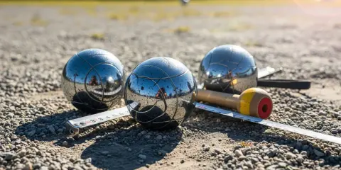 Trois boules de pétanque brillantes, un cochonnet et un mètre sur un terrain de gravier. Le jeu du joueur de boules est prêt.