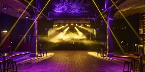 Scenljus och rök fyller en tom lokal i slakthusområdet Stockholm, redo för en kväll med musik och fest.