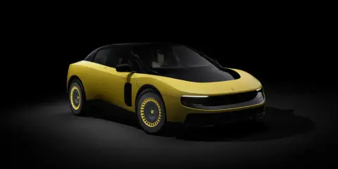 Un'audace Ferrari F244 gialla con tetto nero e cerchi dorati, illuminata da un fascio di luce su sfondo scuro.