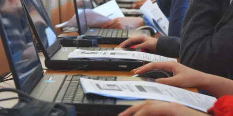 Uczniowie klasy 4 na lekcji informatyki pracują przy komputerach, korzystając z myszek i dokumentów.