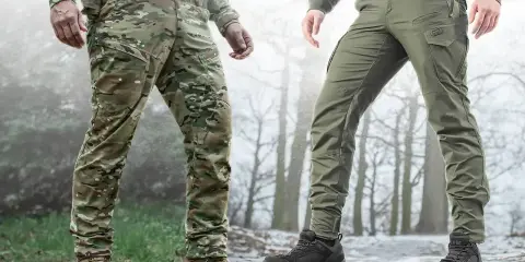 Dwaj mężczyźni w spodniach taktycznych, idealnych na zimowe wyprawy w góry. Jeden w kamuflażu, drugi w zielonych.