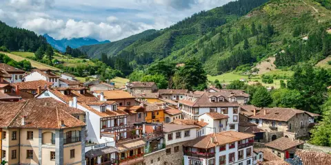 Potes, un pintoresco pueblo en los Picos de Europa, con casas de tejados rojos y montañas verdes de fondo.