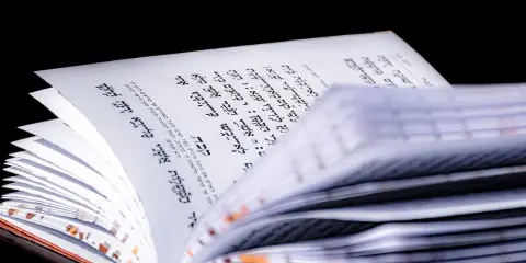 Otwarta księga z hebrajskim tekstem, fragment Psalmu 68. Strony są białe, tekst czarny, na czarnym tle.