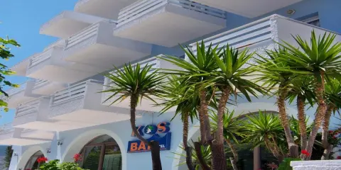 Hotel na Krecie z białymi balkonami i palmami.