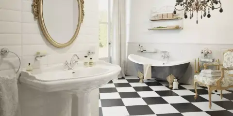 Elegancka, mała łazienka w stylu angielskim z wanną wolnostojącą, umywalką i ozdobnym lustrem.