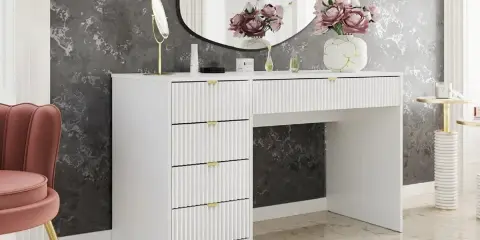 Vitt sminkbord med ribbade lådor och gulddetaljer. En rosa sammetsstol och en rund spegel ger inspiration till ditt sminkbord.