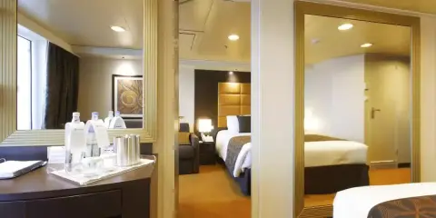 Interno di una cabina MSC Divina con balcone. Letto, specchi e un tavolino con bottiglie d'acqua.