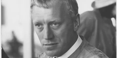 Max von Sydow, en ikonisk skådespelare, blickar intensivt mot kameran. Hans ansikte är känt från många minnesvärda filmer.