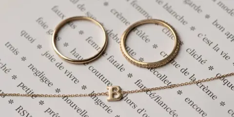 Anelli e collana in oro 14 carati, che significa un gioiello di qualità, su pagine di un libro con parole francesi.