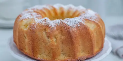 Puszysta babka cytrynowa na oleju Ewy Wachowicz, oprószona cukrem pudrem, prezentuje się apetycznie na białej paterze.