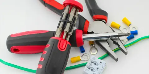 Narzędzia elektryczne i różne rodzaje końcówek kabli, w tym izolowane złączki pierścieniowe i tulejkowe, gotowe do pracy.