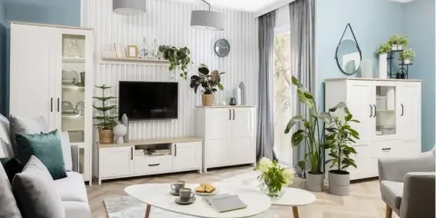 Nowoczesny salon z białymi meblami i dużą ilością zielonych kwiatów.