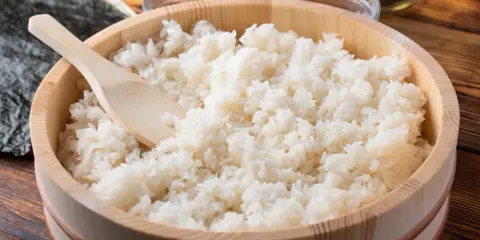 Gotowany ryż do sushi w drewnianej misce z drewnianą łyżką.