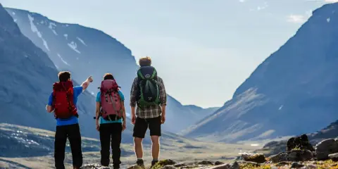 Vandrare med ryggsäckar njuter av den storslagna utsikten över fjällen under en abisko sommar.