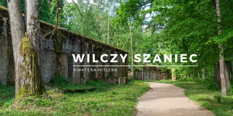 Wilczy Szaniec, dawna kwatera Hitlera, otoczona bujną zielenią. Kamienne mury i leśna ścieżka tworzą atmosferę minionych czasów.