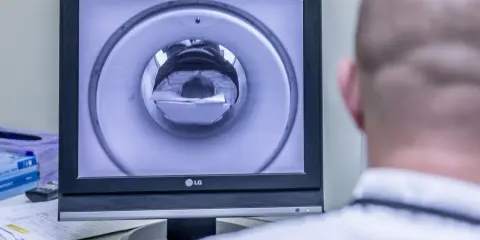 Opis rezonansu magnetycznego głowy. Na ekranie widać wnętrze aparatu MRI, przez które przechodzi pacjent.