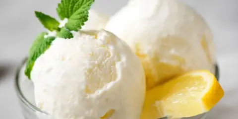 Delicioso helado de limón casero en copa de cristal, adornado con menta fresca y rodajas de limón.
