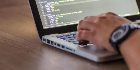 Dłoń pisze kod CSS, optymalizując pliki do wersji min.