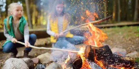 Dzieci przy ognisku w lesie, iskry tańczą w powietrzu. Uważajcie, by nie wywołać pożaru lasu!