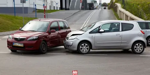 Wypadek samochodowy. Czerwone i srebrne auto po kolizji. Po takim zdarzeniu warto sprawdzić, jak sprawdzić ile mam zniżek na ubezpieczenie.