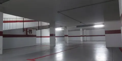 Un garaje particular recién pintado, con líneas rojas en el suelo y paredes blancas con franjas rojas.