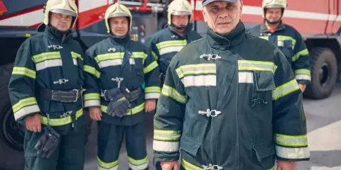Strażacy w pełnym rynsztunku przy wozie strażackim. Zastanawiasz się, ile zarabia strażak?