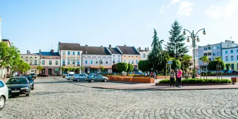 Rynek w Krapkowicach z kolorowymi kamienicami i brukowaną nawierzchnią. Atrakcje miasta widoczne w tle.