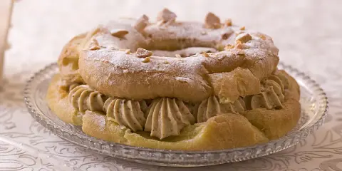 Un Paris-Brest rond, saupoudré de sucre glace et d'amandes effilées, garni d'une généreuse crème diplomate.