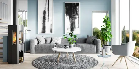Sala de estar moderna con paredes de color azul polvoriento, sofá gris, chimenea y arte abstracto.