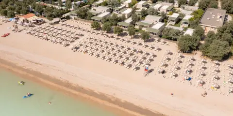 Domenica di sole sulla spiaggia di Rivazzurra, con ombrelloni, lettini e bagnanti che si godono il mare.