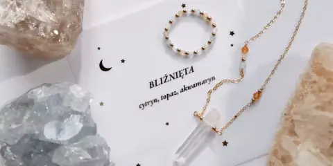 Delikatna biżuteria z kamieniami, w tym akwamaryn, otoczona surowymi kryształami.