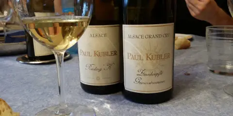 Verre de vin blanc et deux bouteilles Paul Kubler, Riesling et Gewurztraminer. Quel vin pour cuire la choucroute ? Le Gewurztraminer est un excellent choix.
