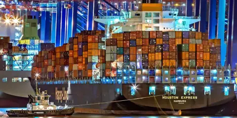 Nocą w porcie holownik pomaga wielkiemu kontenerowcowi. Spedytor, kto to? To osoba organizująca transport.