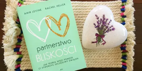 Książka "Partnerstwo bliskości. Jak teoria więzi pomoże Ci stworzyć szczęśliwy związek" obok serca z lawendą.