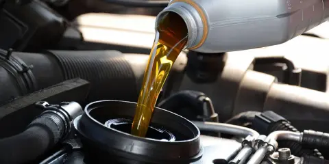 Verser de l'huile minérale ou synthétique dans le moteur d'une voiture.