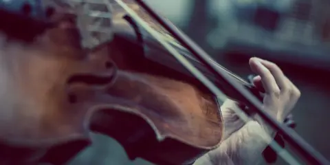 Dłoń gra na skrzypcach Stradivarius, wydobywając z nich magiczne dźwięki.