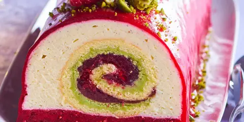 Bûche de Noël aux pistaches et framboises, un délice visuel et gustatif. La recette buche pistache framboise parfaite pour les fêtes.