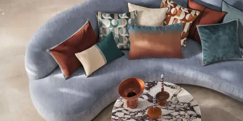 Sofá curvo gris con cojines de terciopelo y estampados geométricos. Un diseño moderno y acogedor.