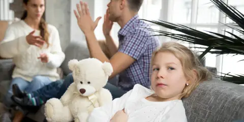 Smutna dziewczynka z misiem, podczas gdy jej rodzice się kłócą. Mąż wyprowadził się z domu, a rozwód jest nieunikniony.
