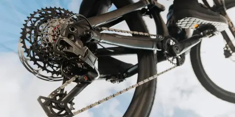 Nahaufnahme einer SRAM Schaltung am Fahrrad. Die Kette läuft über die Kassette, während ein Schuh auf dem Pedal zu sehen ist. Perfekt, um die SRAM Schaltung einzustellen.