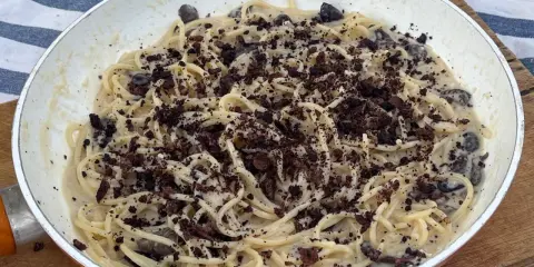 Spaghetti cremosi con olive nere e una spolverata di cacao amaro, un'originale pasta alla cenere.