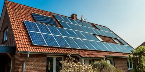 Ett tegelhus med solpaneler på taket, en del av solenergi historia.