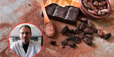 Czy gorzka czekolada jest zdrowa? Naukowiec w białym fartuchu analizuje ziarna kakao, tabliczkę gorzkiej czekolady i kakao w proszku.