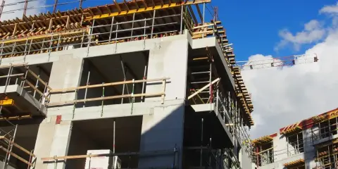 Rohbau eines Mehrfamilienhauses im Rahmen der Entwicklung von urbane gebiete. Gerüste und Betonstrukturen unter blauem Himmel.