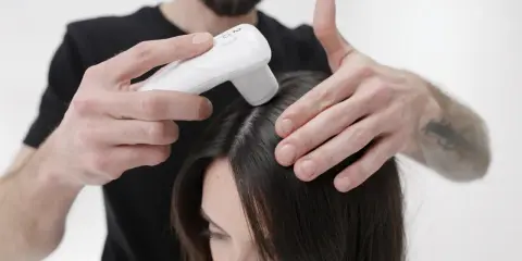 Application d'un appareil sur le cuir chevelu, peut-être pour évaluer les effets secondaires de Furterer Triphasic Progressive.