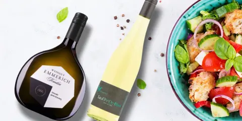 Zwei Flaschen Wein, eine davon eine Scheurebe aus Franken, neben einem bunten Salat.